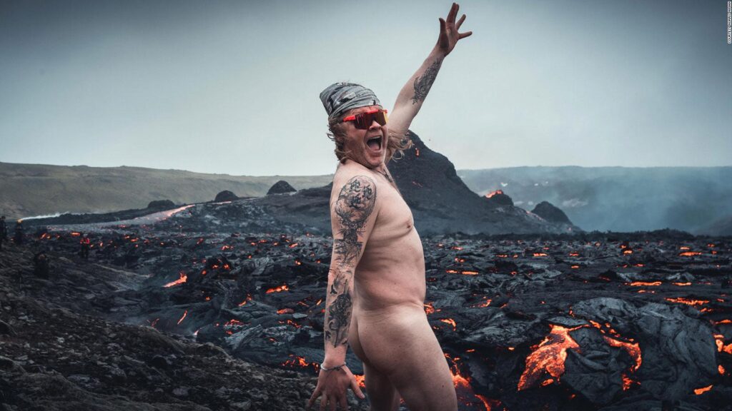 man naked in front of a volcano
