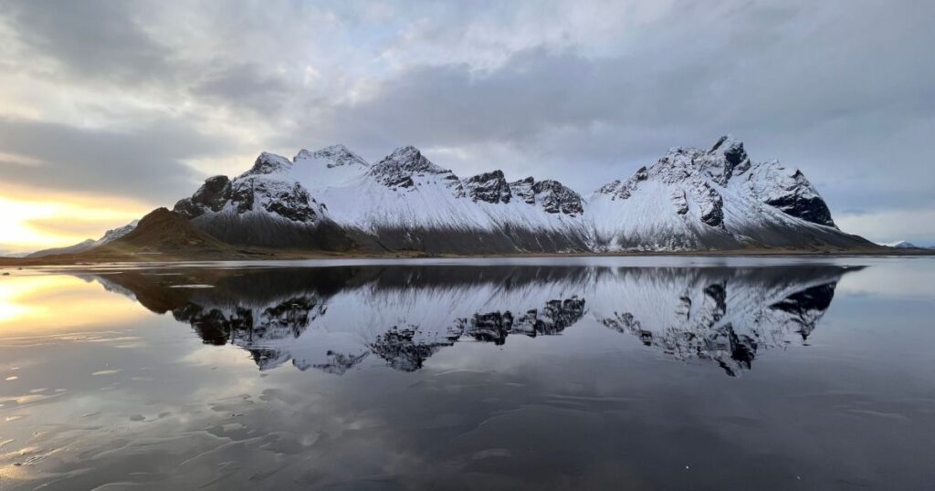 Snow-covered Vestrahorn mountains reflected in the water in southeast Iceland